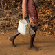 A woman carries an improvised plastic can to fetch water from a well outside Denganmal village